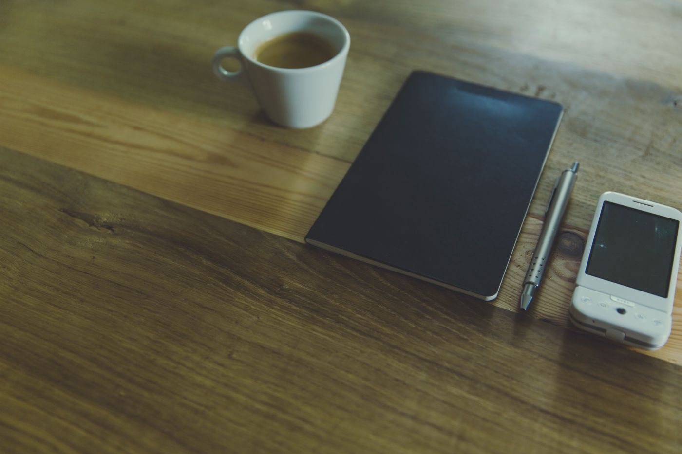 Schreibtisch mit Notizbuch, Stift und Kaffeetasse